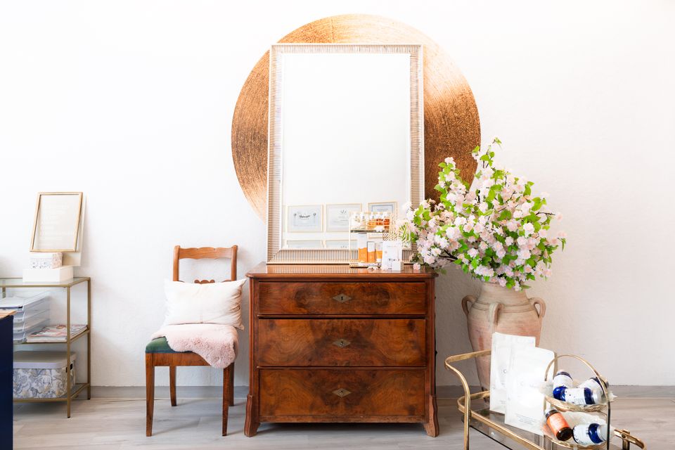Spiegel mit goldenem Kreis, Kommode und Blumen im Studio von Emotion Skin Care